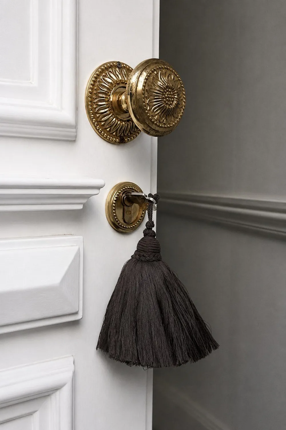 A brass door handle with a heavy tassel hanging from the key