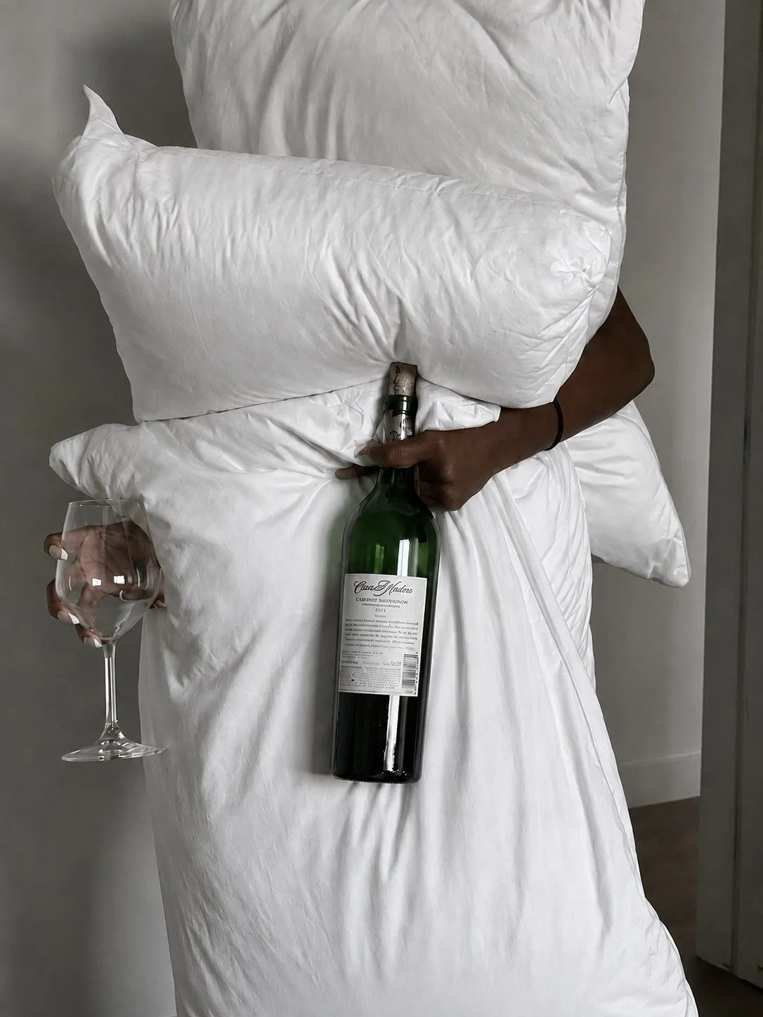 A guest carrying the duvet, a bottle and a glass through the room