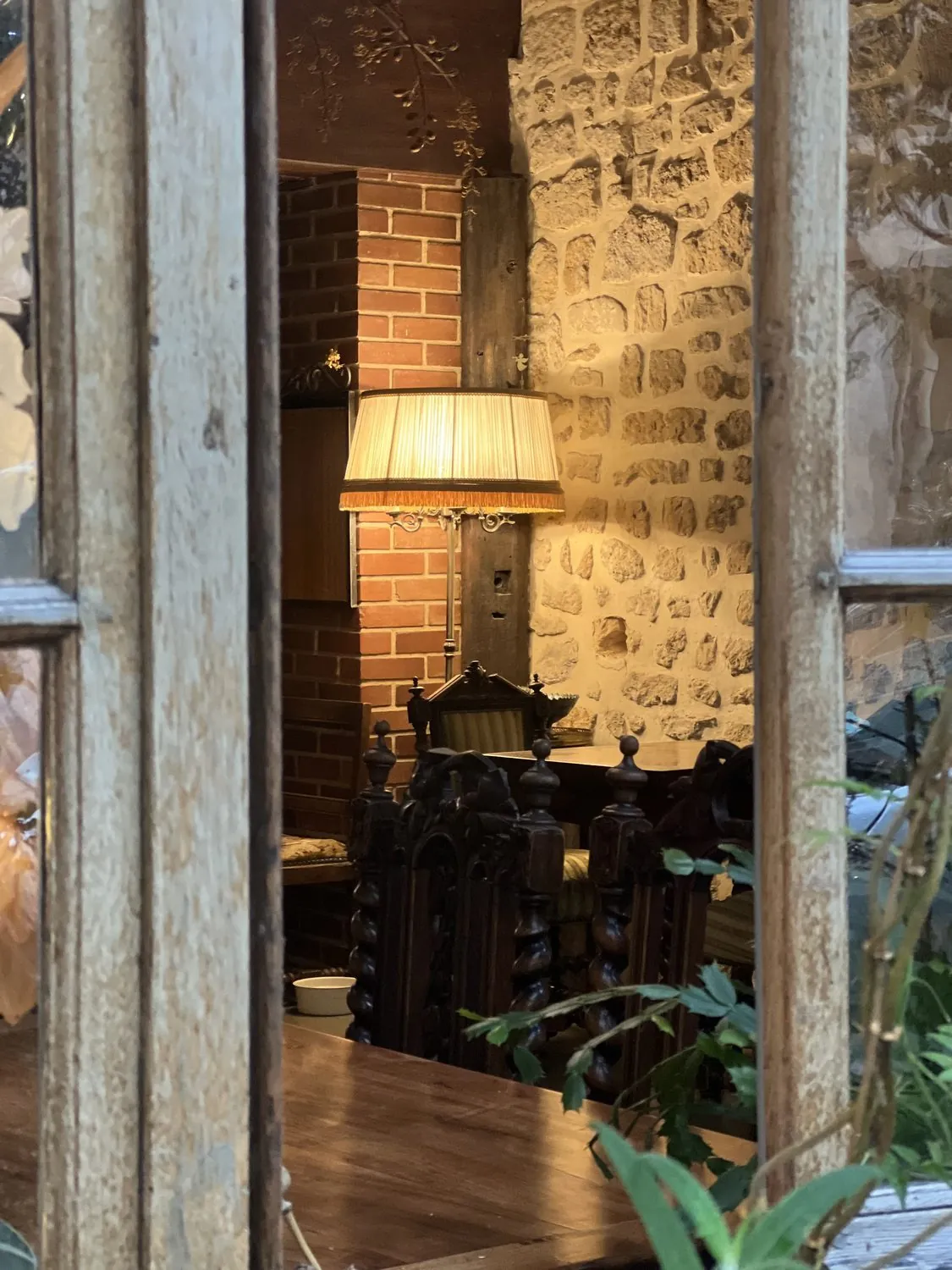A room seen through an old window — brick, stone, one lamp lit in the afternoon