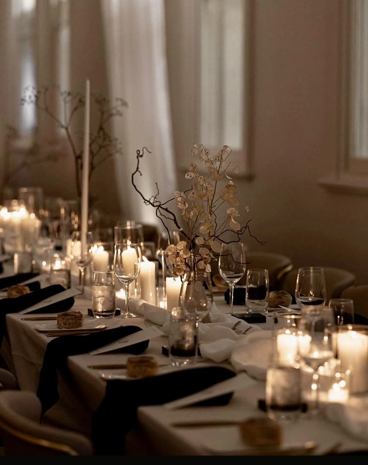 A long table laid and lit, mid-service, in a luxury dining room