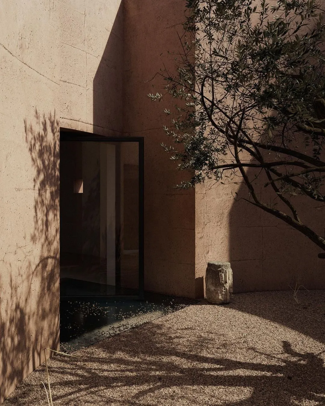 A doorway set into a plaster wall, shadow falling across the threshold